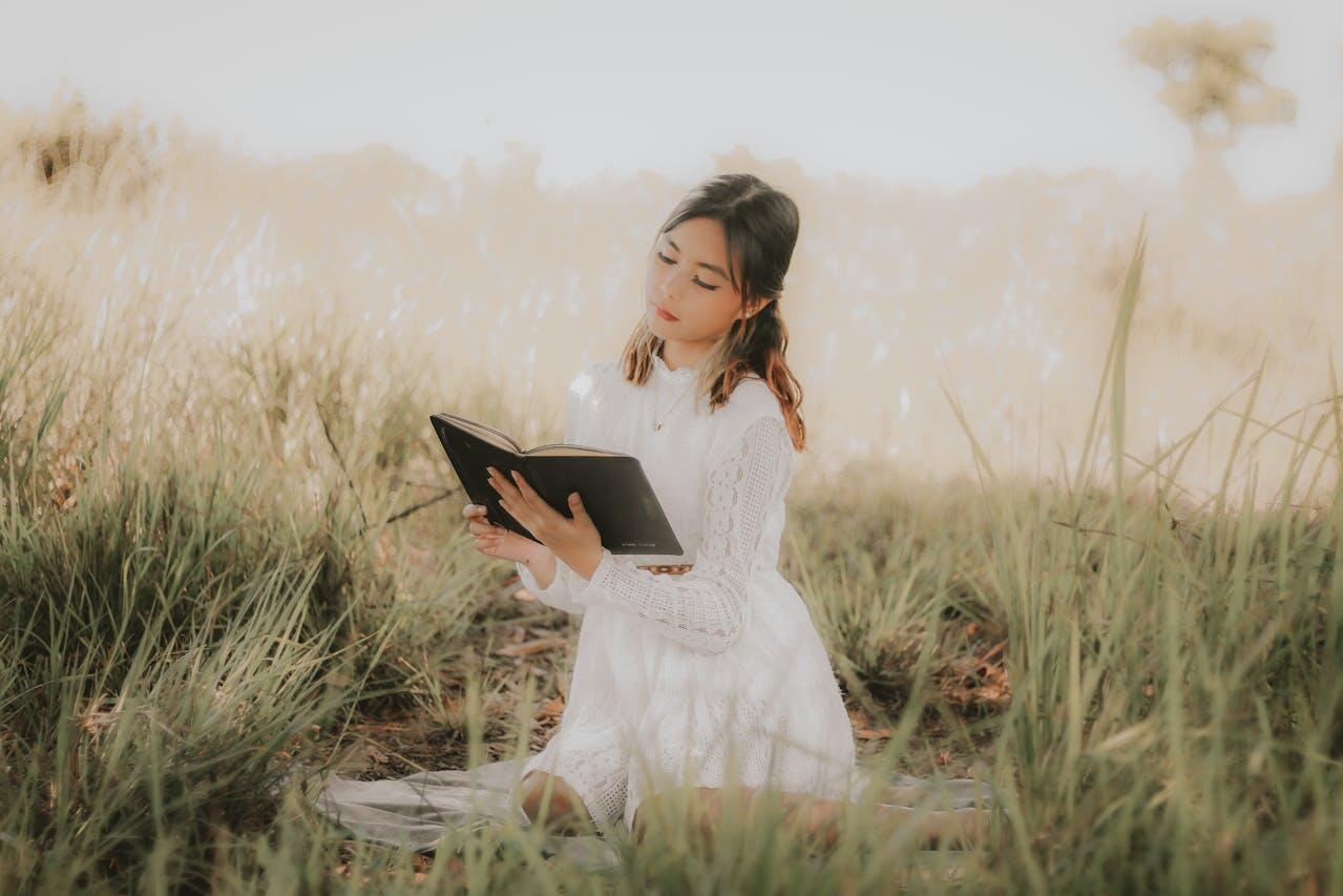 jeune femme en robe longue blanche dans la nature lisant