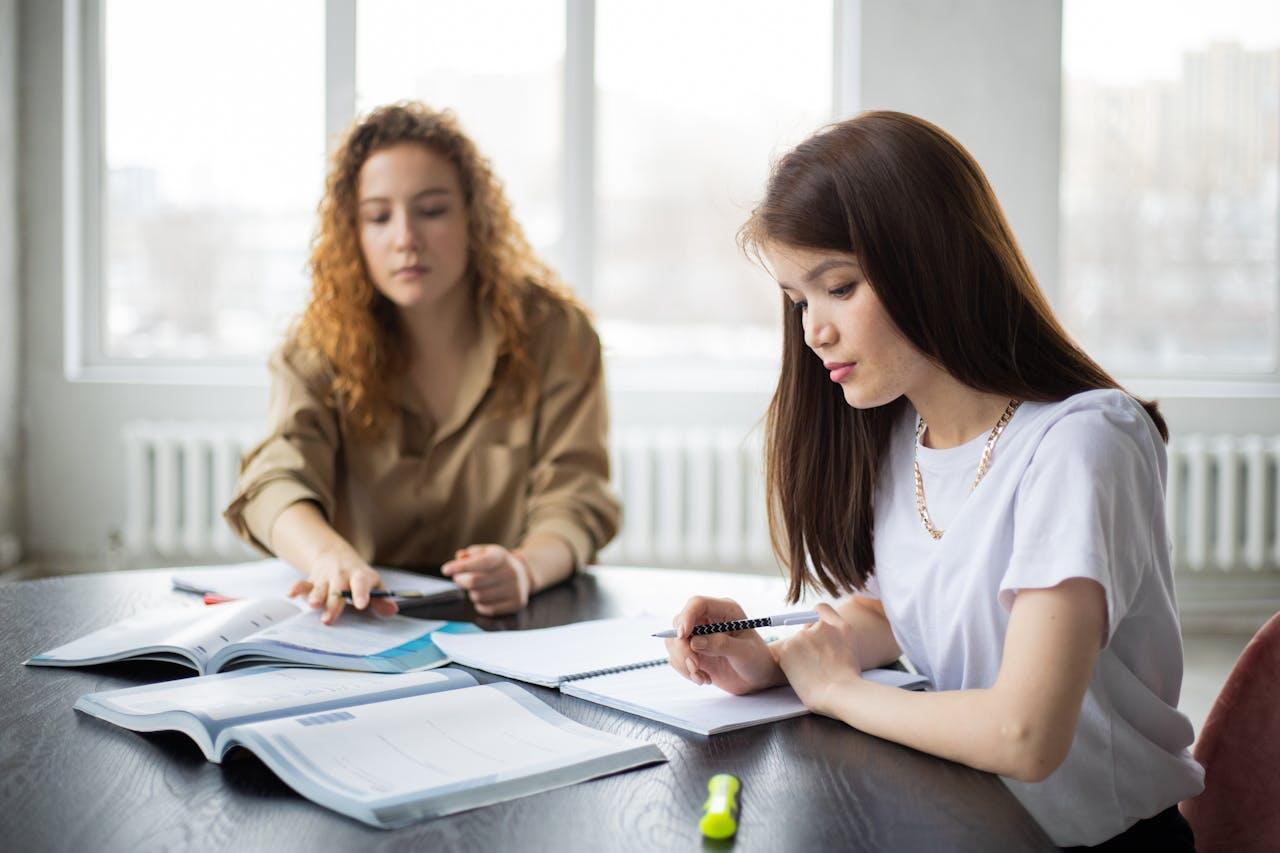 deux jeunes femmes etudiant avec cahier et stylo a une table