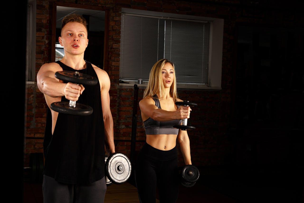 un jeune homme et une jeune femme en tenue de sport faisant des alteres à la salle de sport