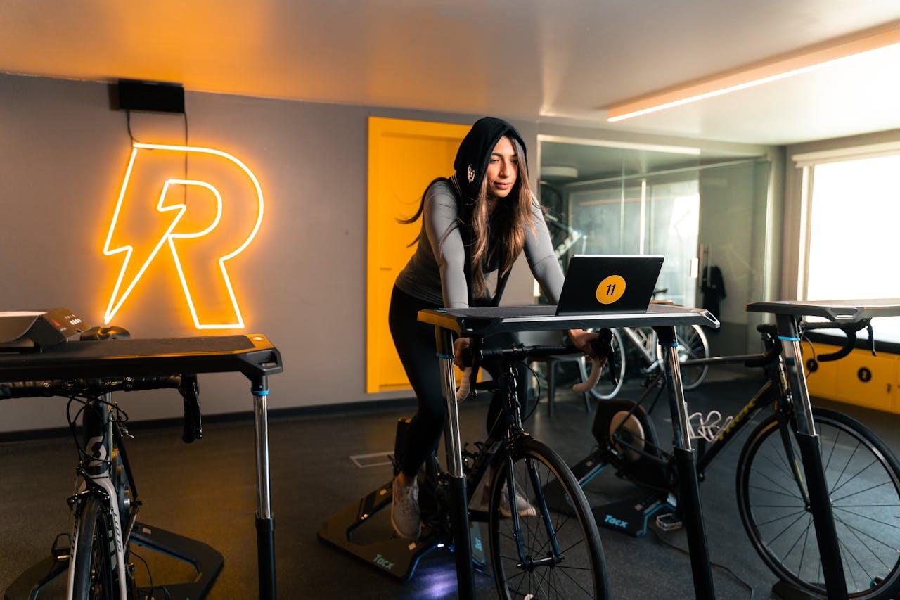 jeune femme faisant du velo spinning dans une salle de sport en ecotant de la musique