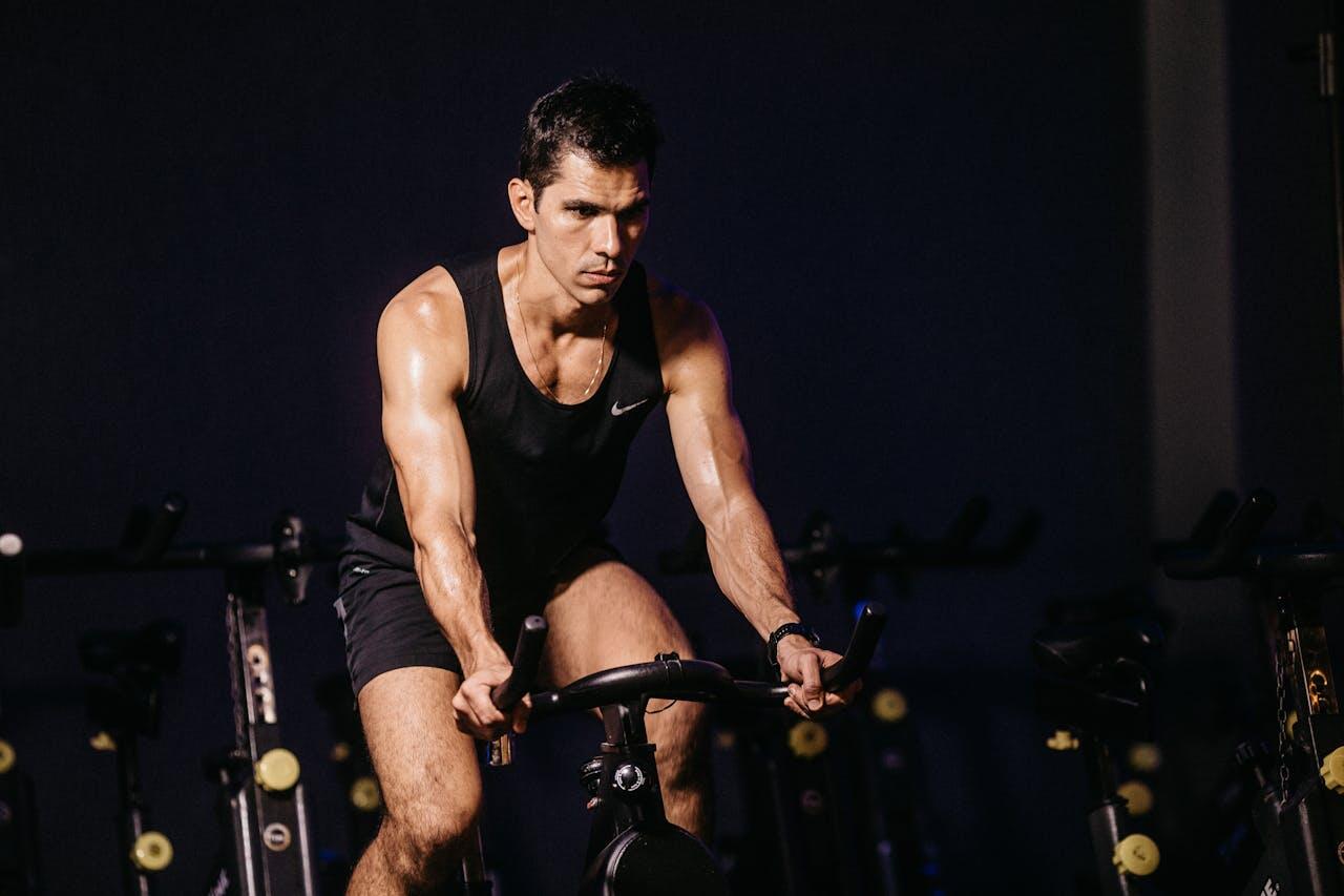 homme muscle faisant du velo spinning