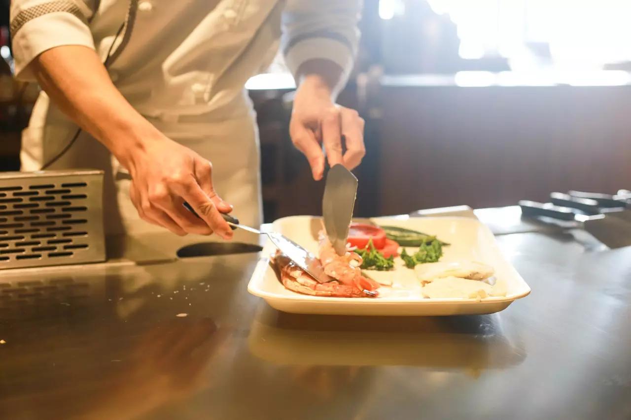 chef qui met en assiette un plat avec de la viande