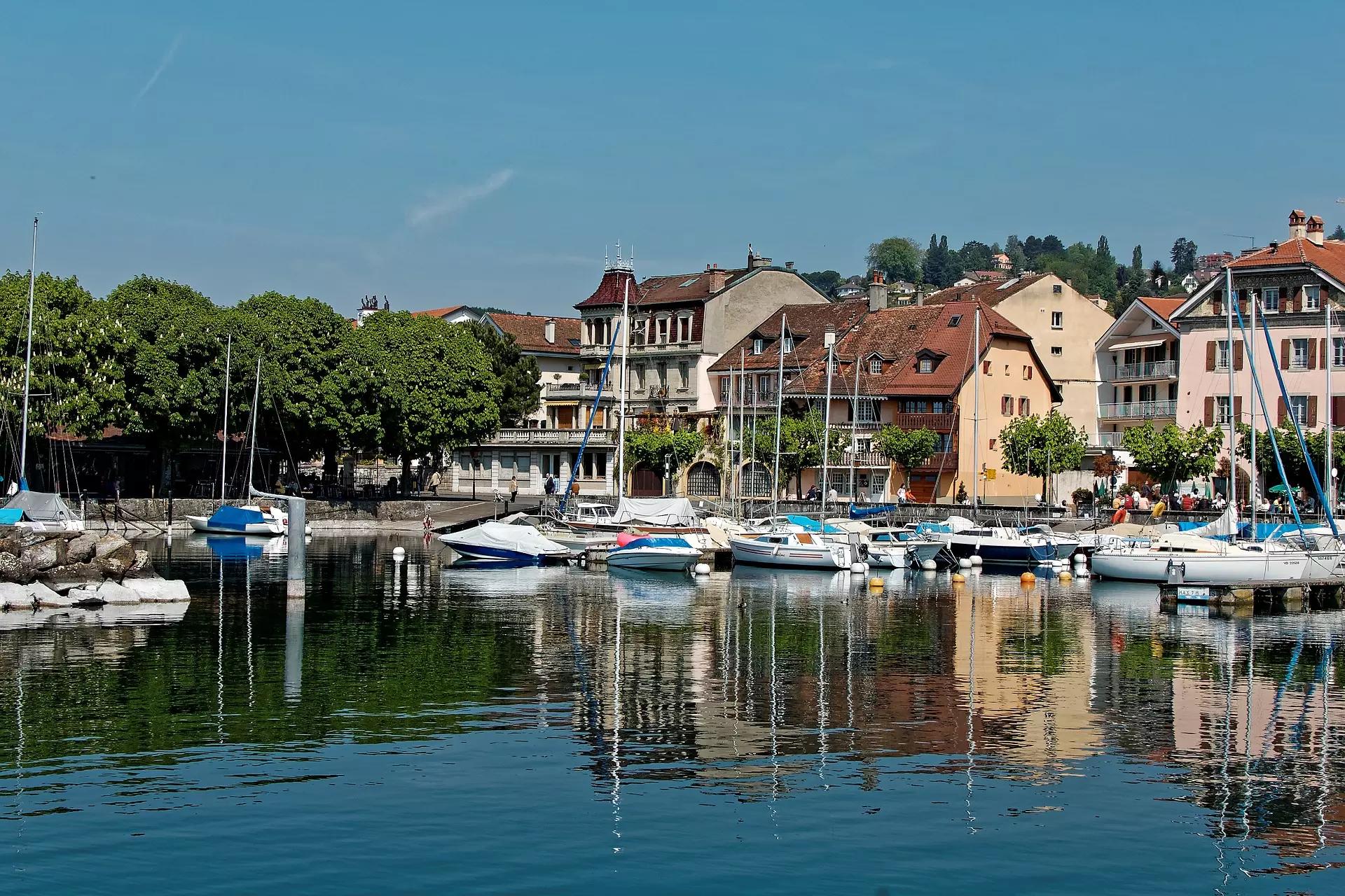 Maisons roses à Lausanne se trouvant au bord de l'eau, dont une petite partie est recouverte de bateaux