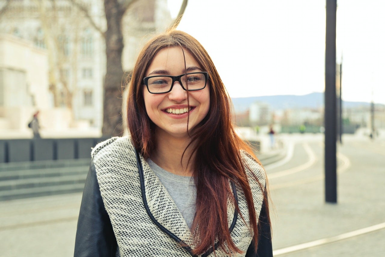 jeune adolescente brune aux cheveux longs a lunettes souriant
