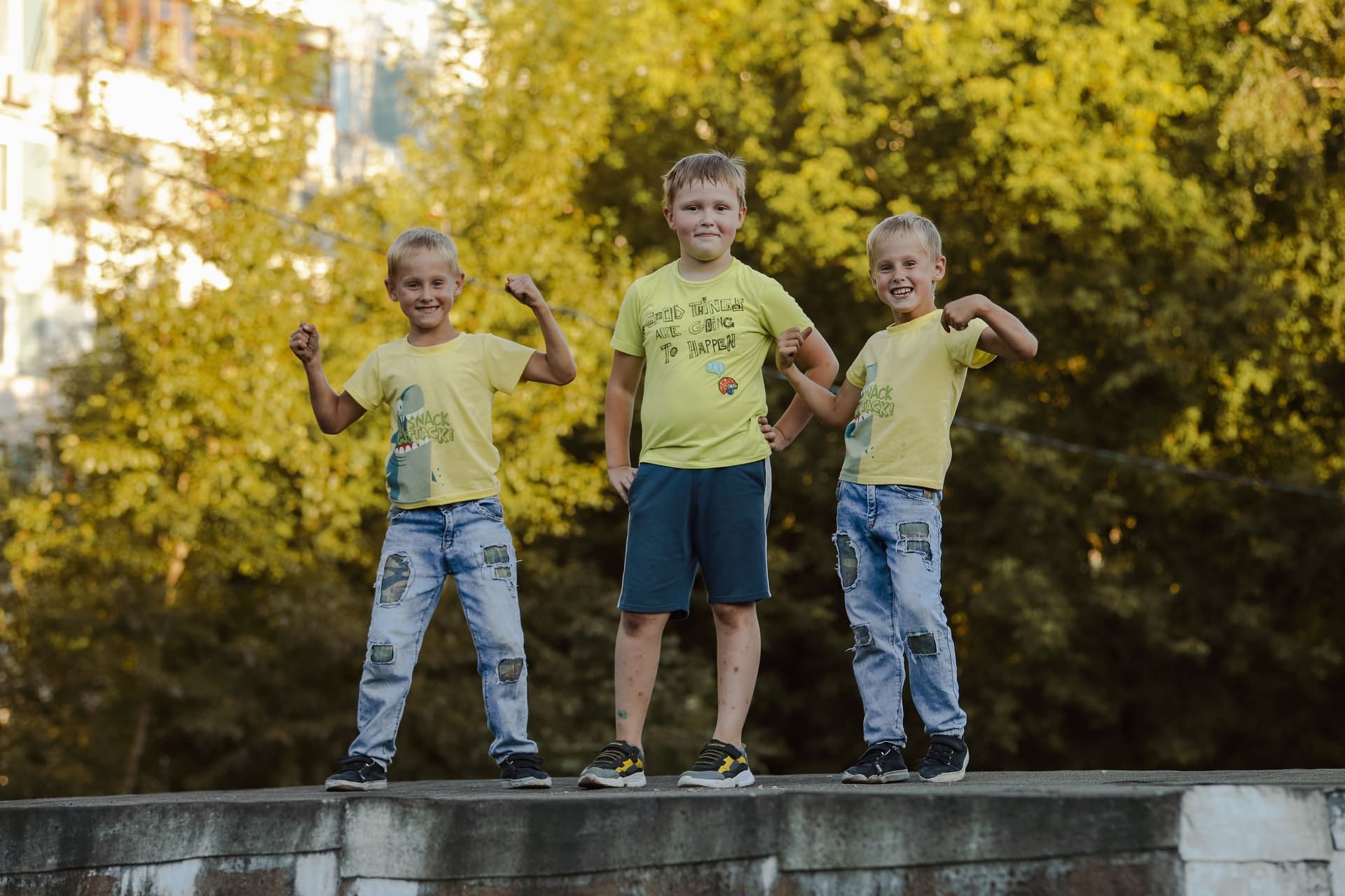 trois enfants debout sur un muret
