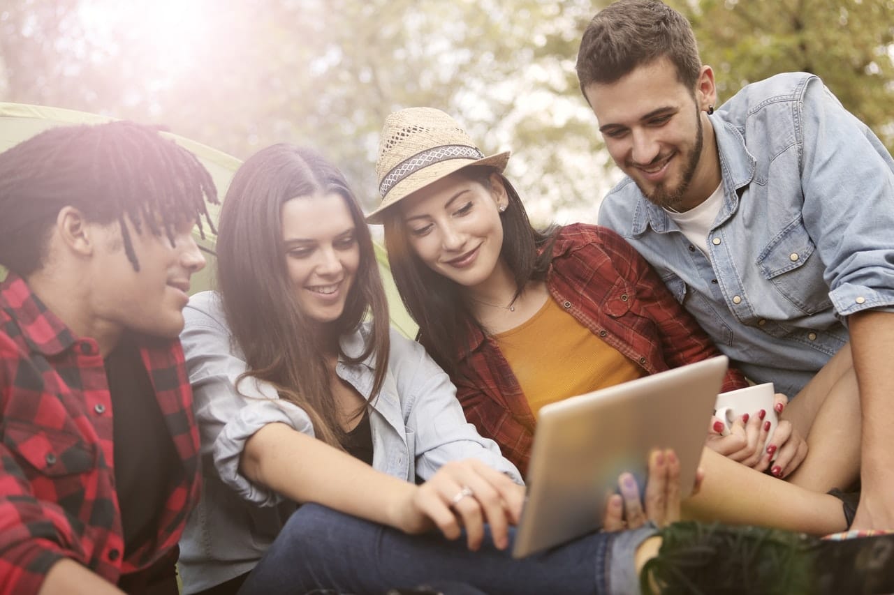 quatre jeunes dans l'herbe regardant un ordinateur