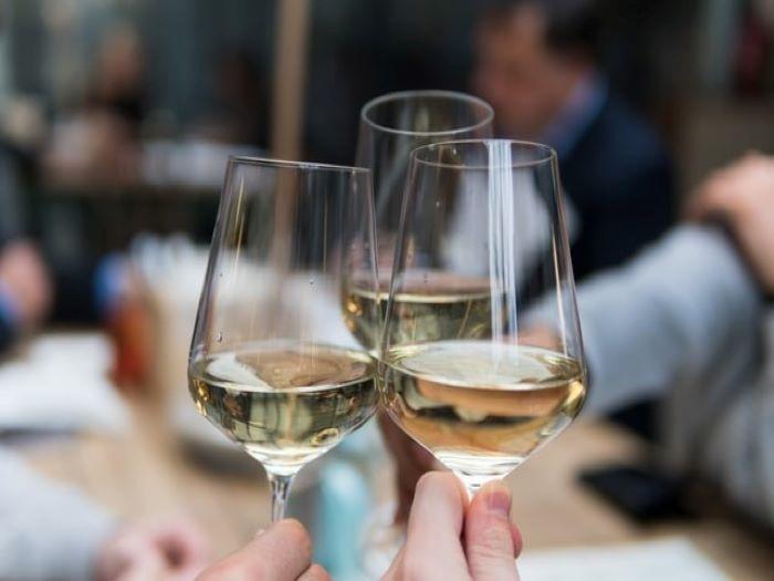 Personnes trinquant avec trois coupes de vin blanc