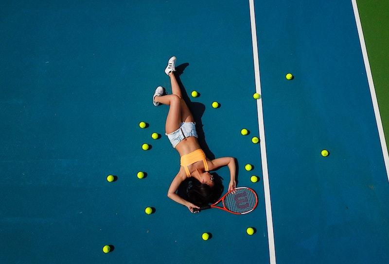 Une joueuse allongée au milieu des balles de tennis