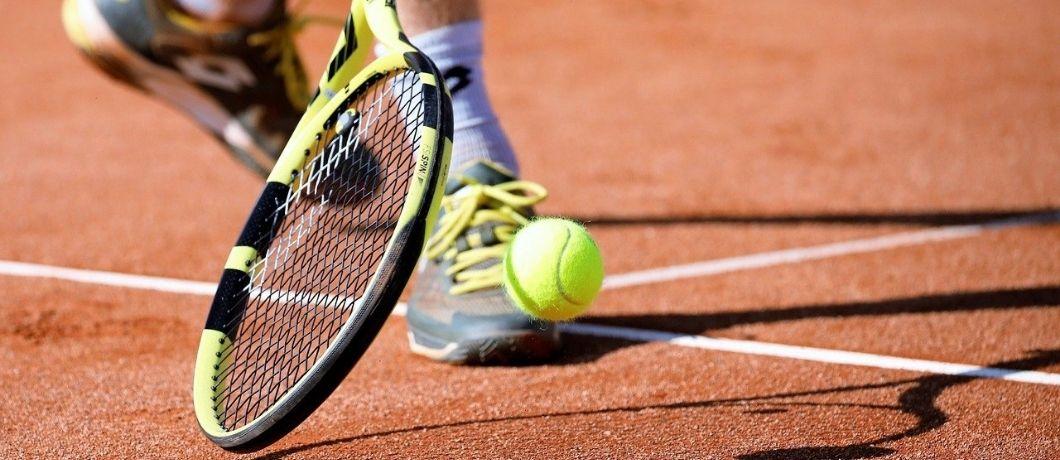 raquette et balle de tennis sur court orange