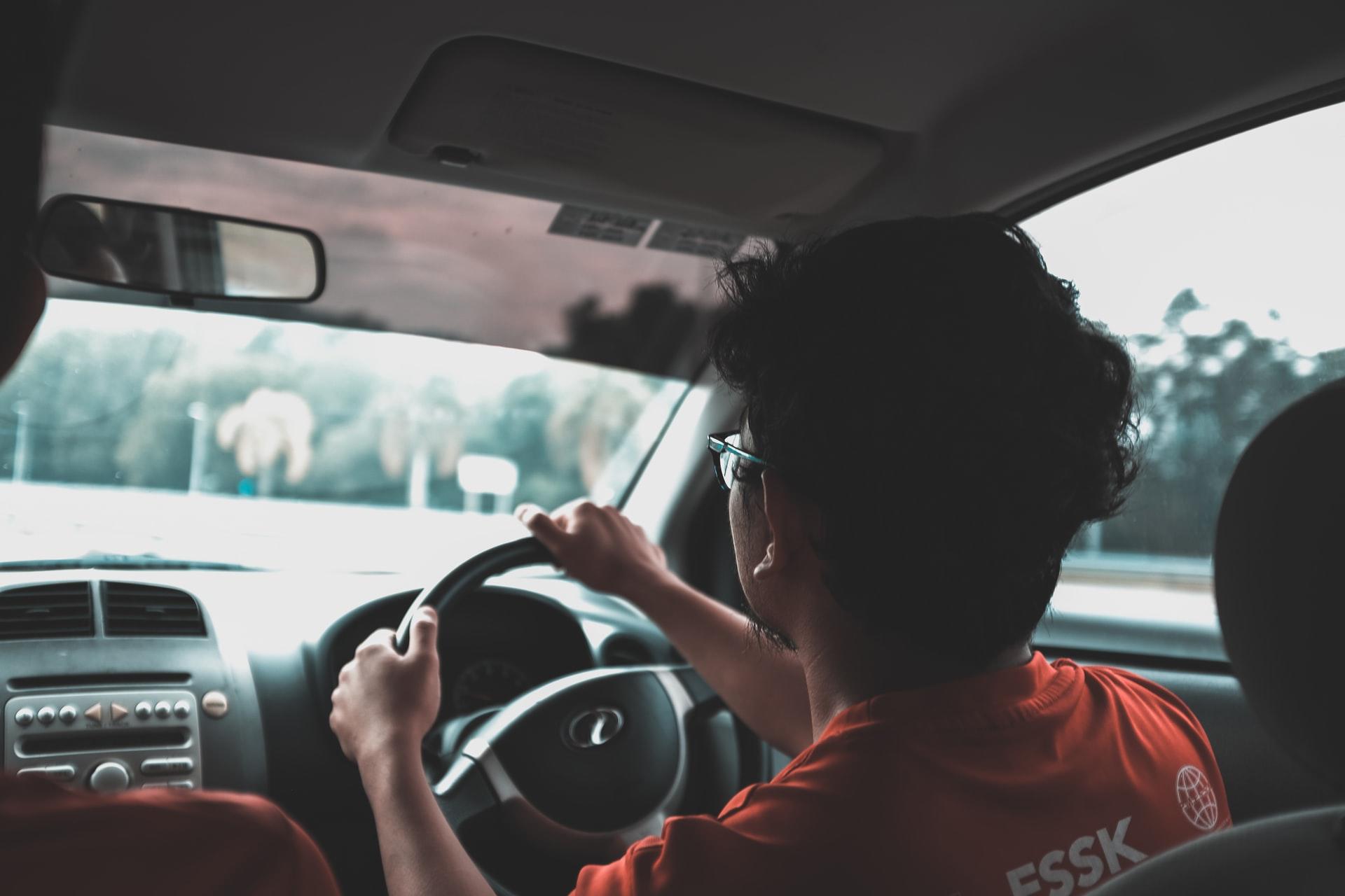 jeune homme brun à lunettes conduisant