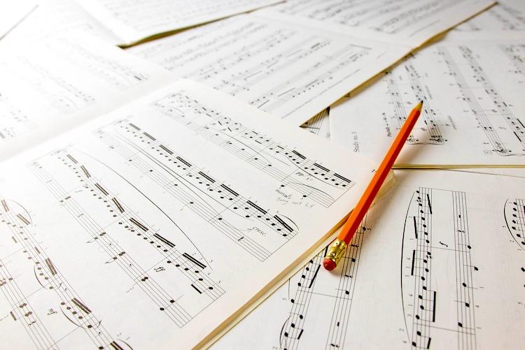 Un crayon posé sur des partitions de solfège