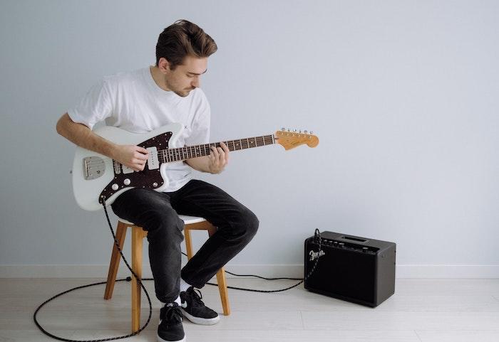 Homme assis qui joue de la guitare électrique