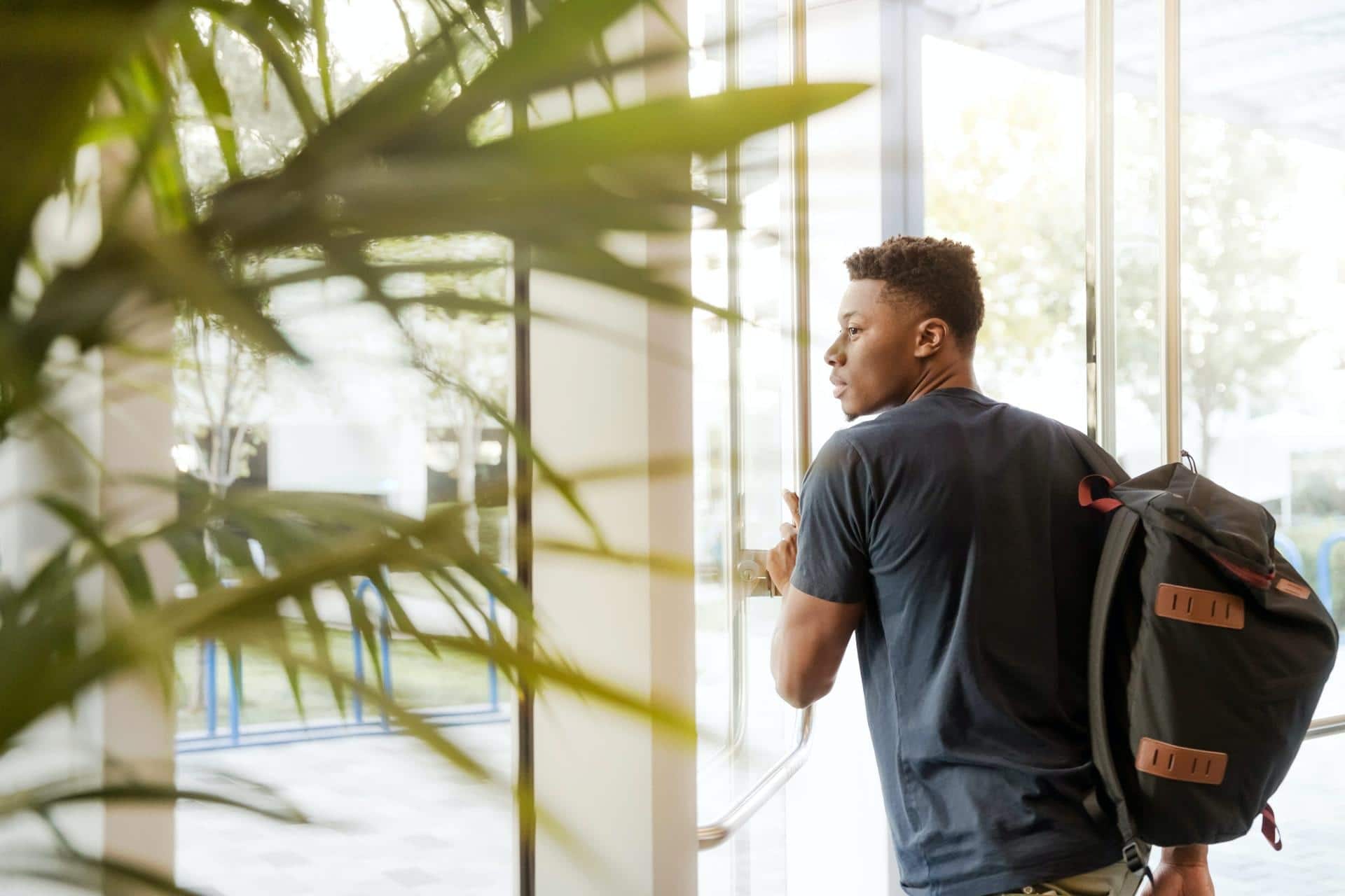 jeune homme sortant de la fac avec son sac à dos