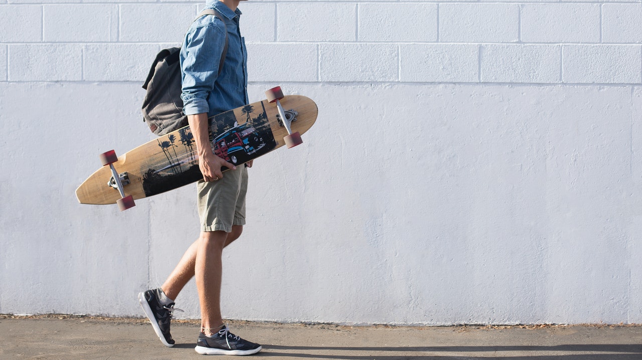 jeune en short portant son skate à la main