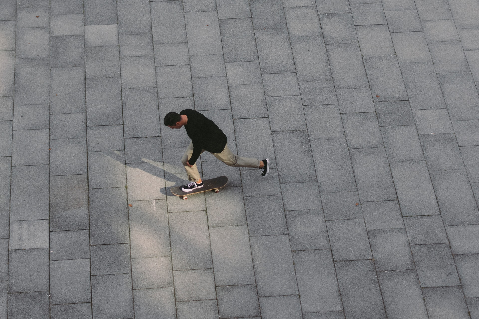 homme roulant avec son skate sur des pavés