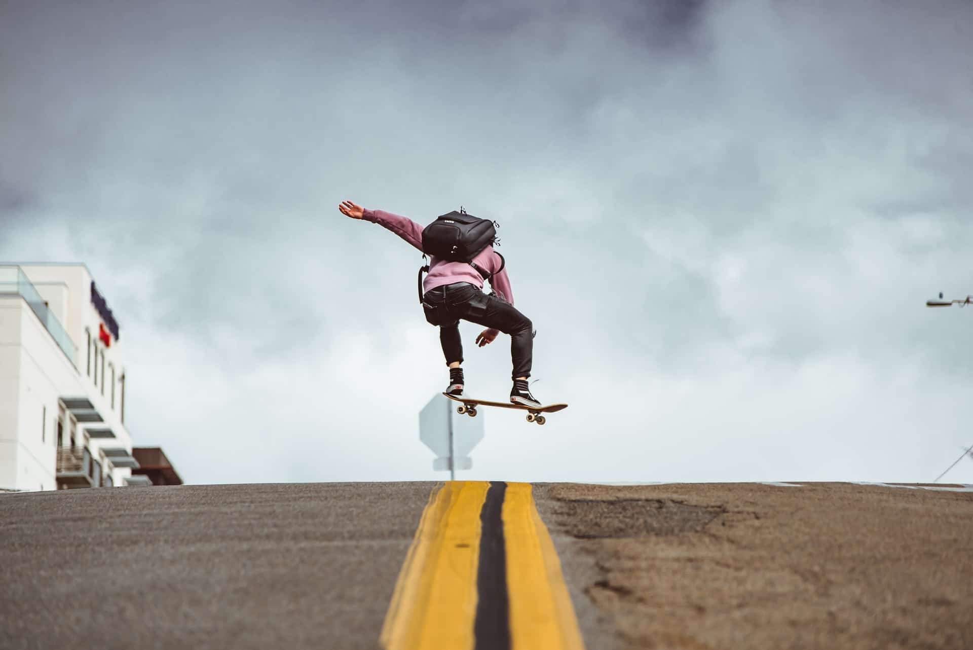 jeune en sac à dos effectuant un trick avec son skateboard