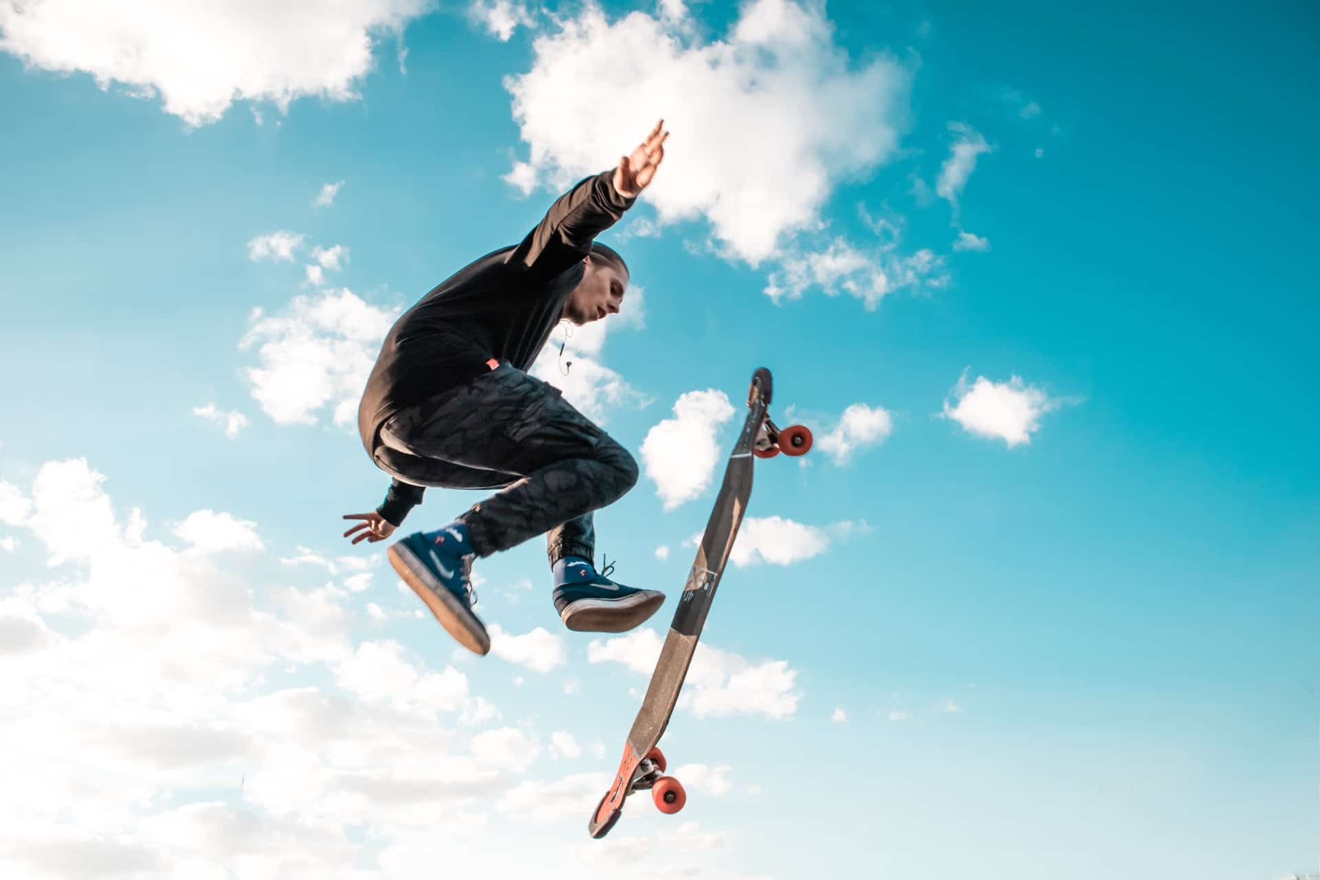 jeune homme effectuant un saut avec son skate dans le ciel