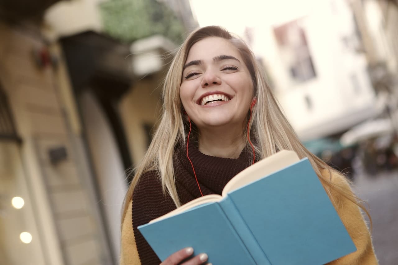 jeune fille blonde souriant avec un livre