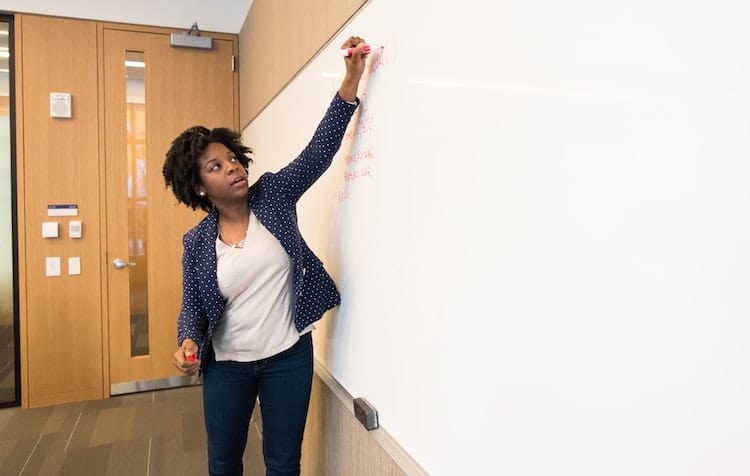 Une femme écrit sur un tableau