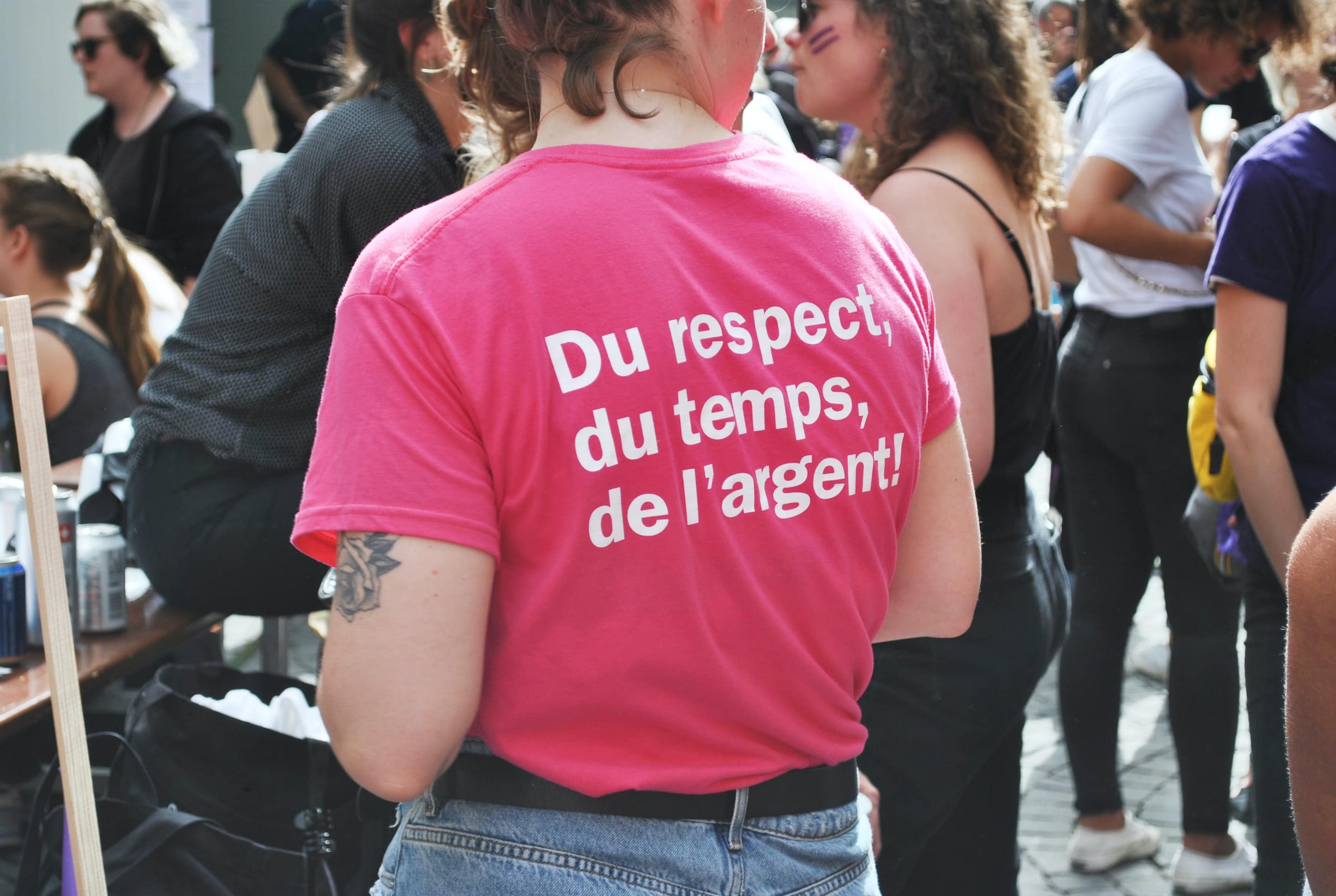Femme qui porte un tshirt rose avec l'inscription "du respect, du temps, de l'argent" 