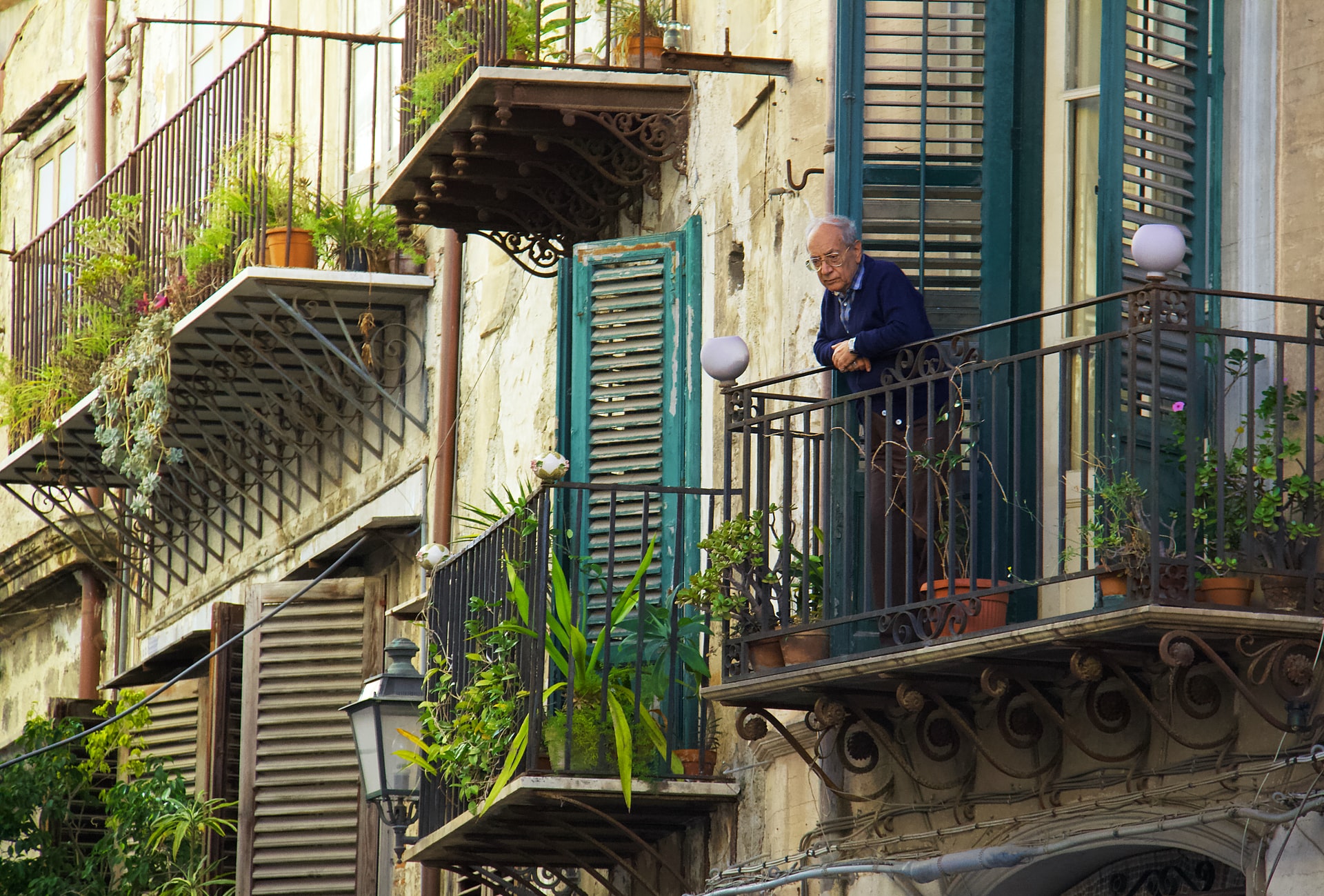homme au balcon regardant la rue
