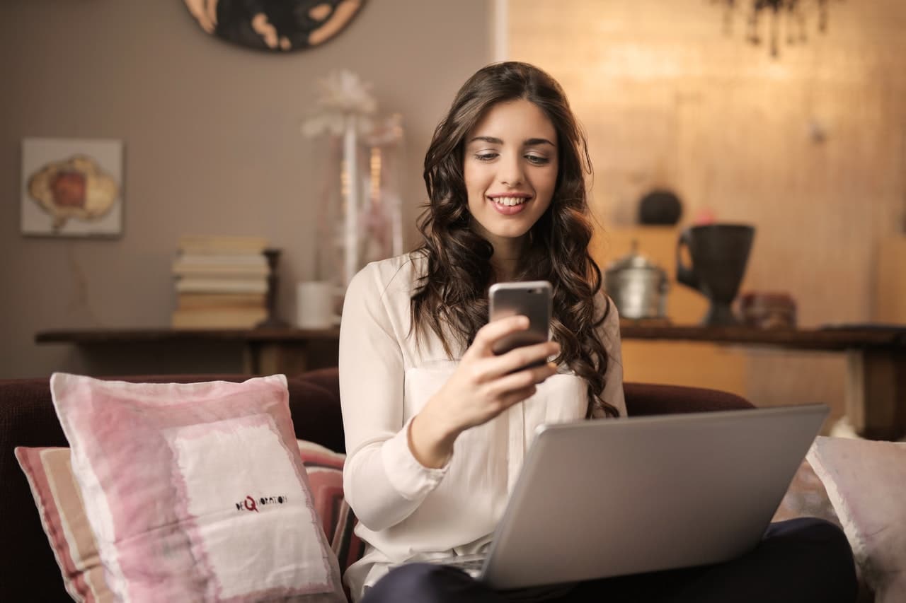 jeune femme souriante avec ordinateur et telephone