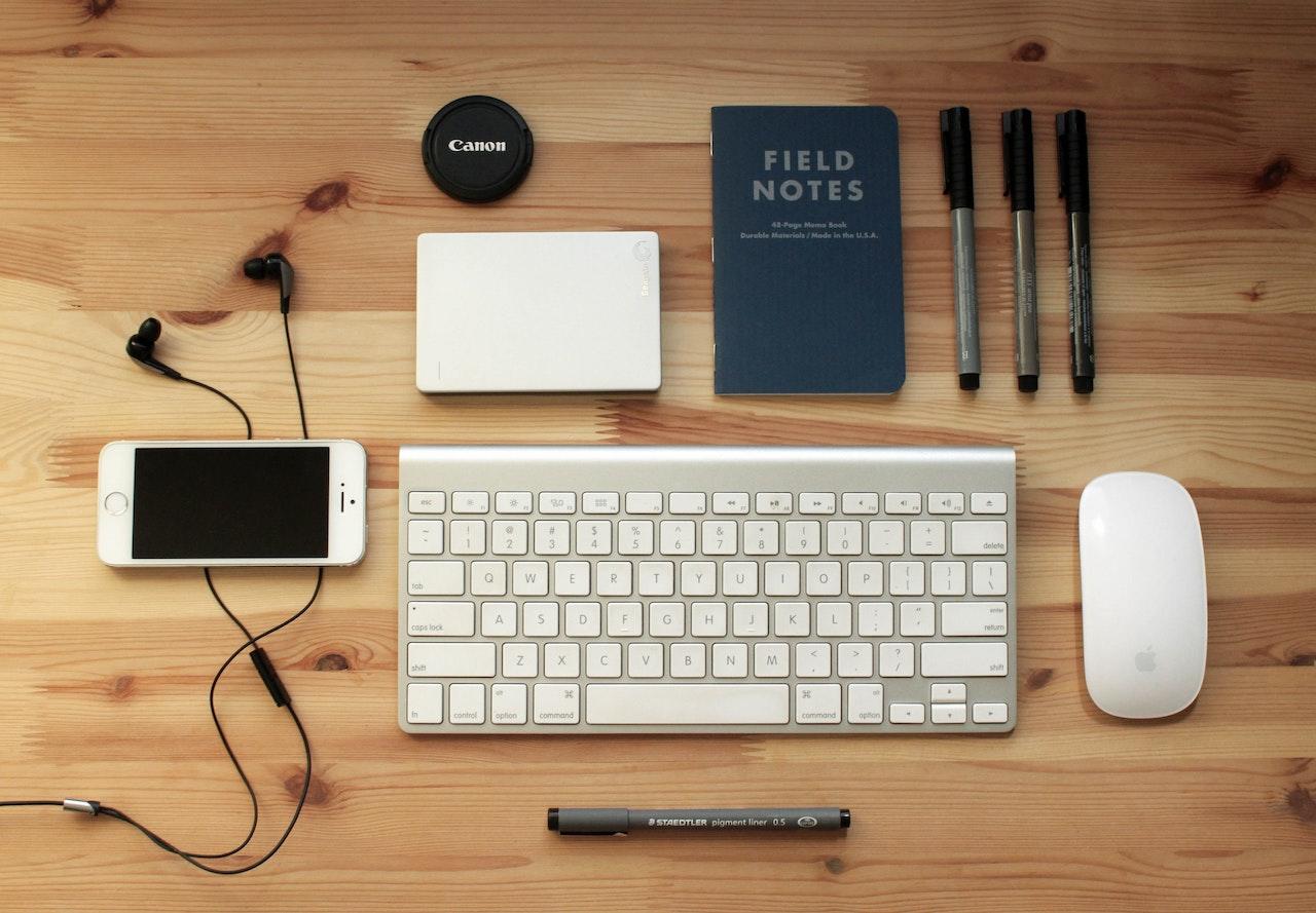 clavier sur une table entoure de stylos, carnet et smartphone