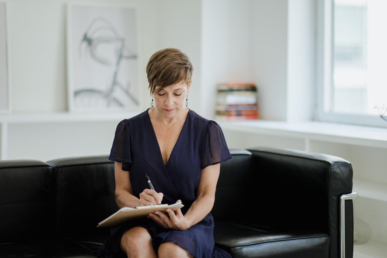 femme en robe bleue prenant des notes sur un canape