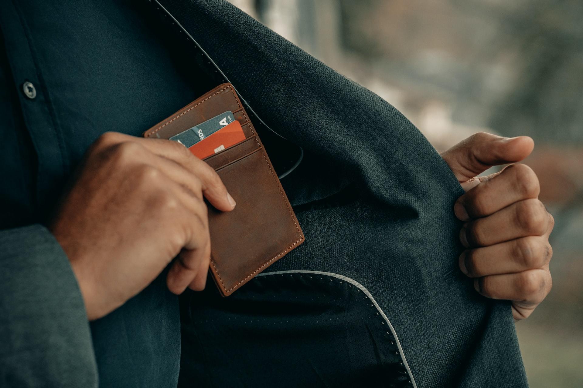 homme rangeant son porte feuille dans la poche interieure de son manteau