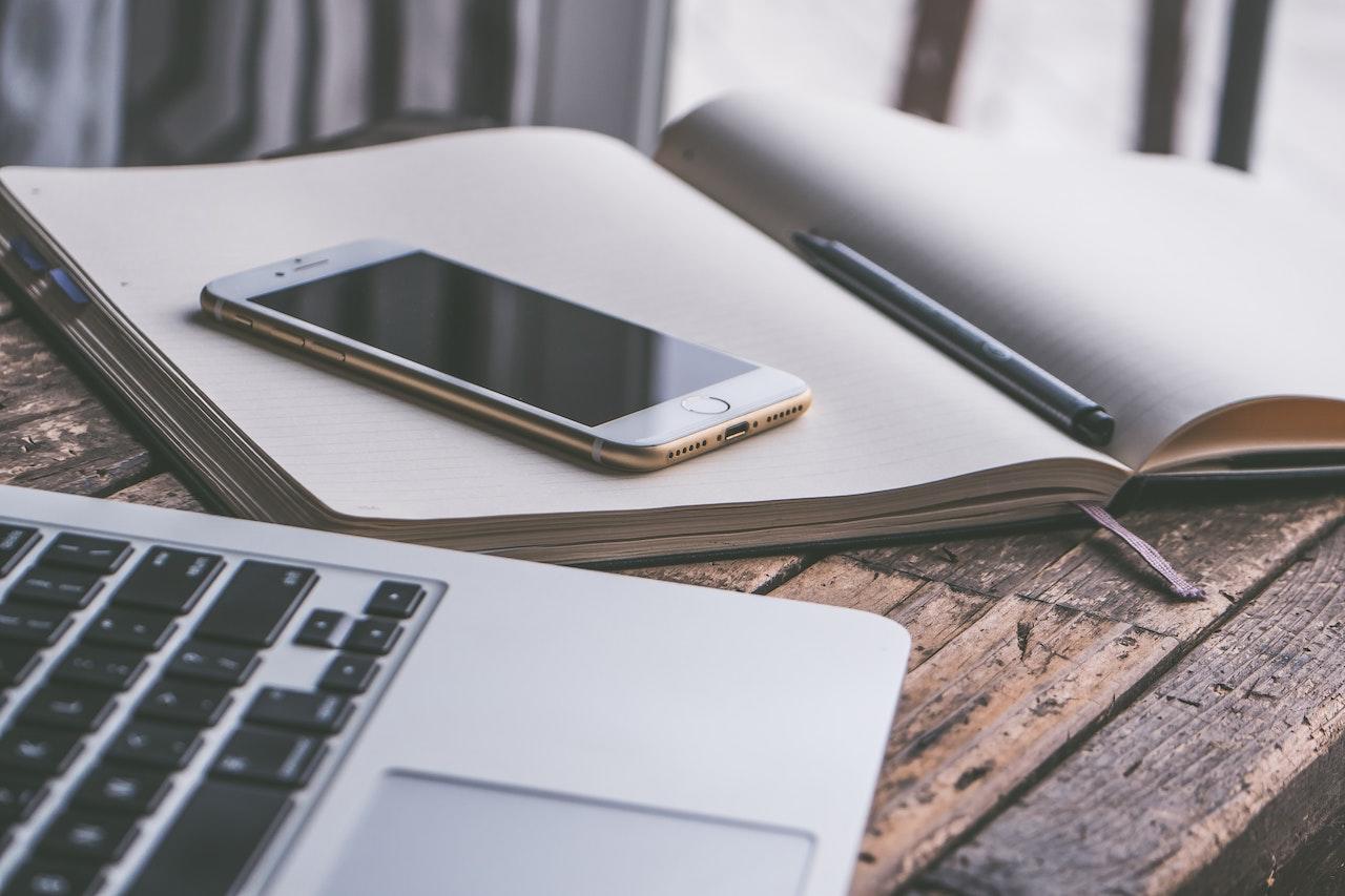 laptop, cahier, crayon et smartphone poses en vrac sur une table
