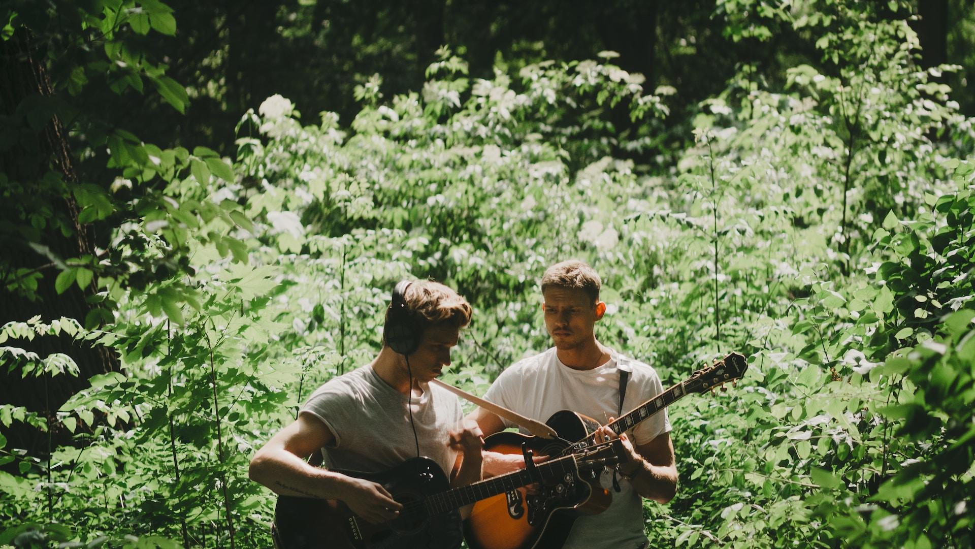 Deux personnes qui jouent à la guitare dans la nature.