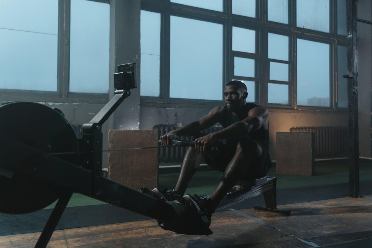 homme noir concentre sur son rameur en salle de sport