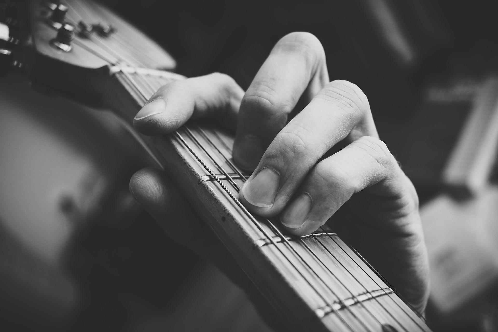 Main et guitare en noir et blanc.