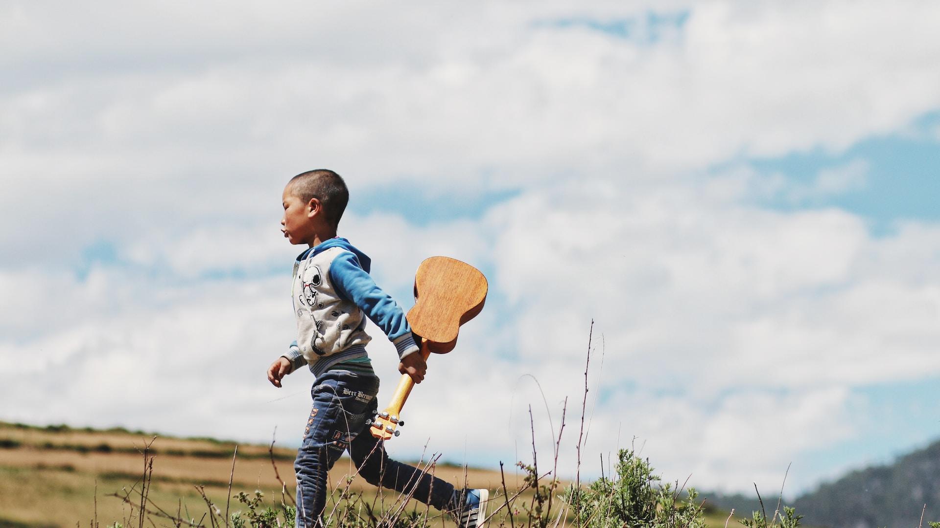 Jeune garçon qui court avec une guitare.