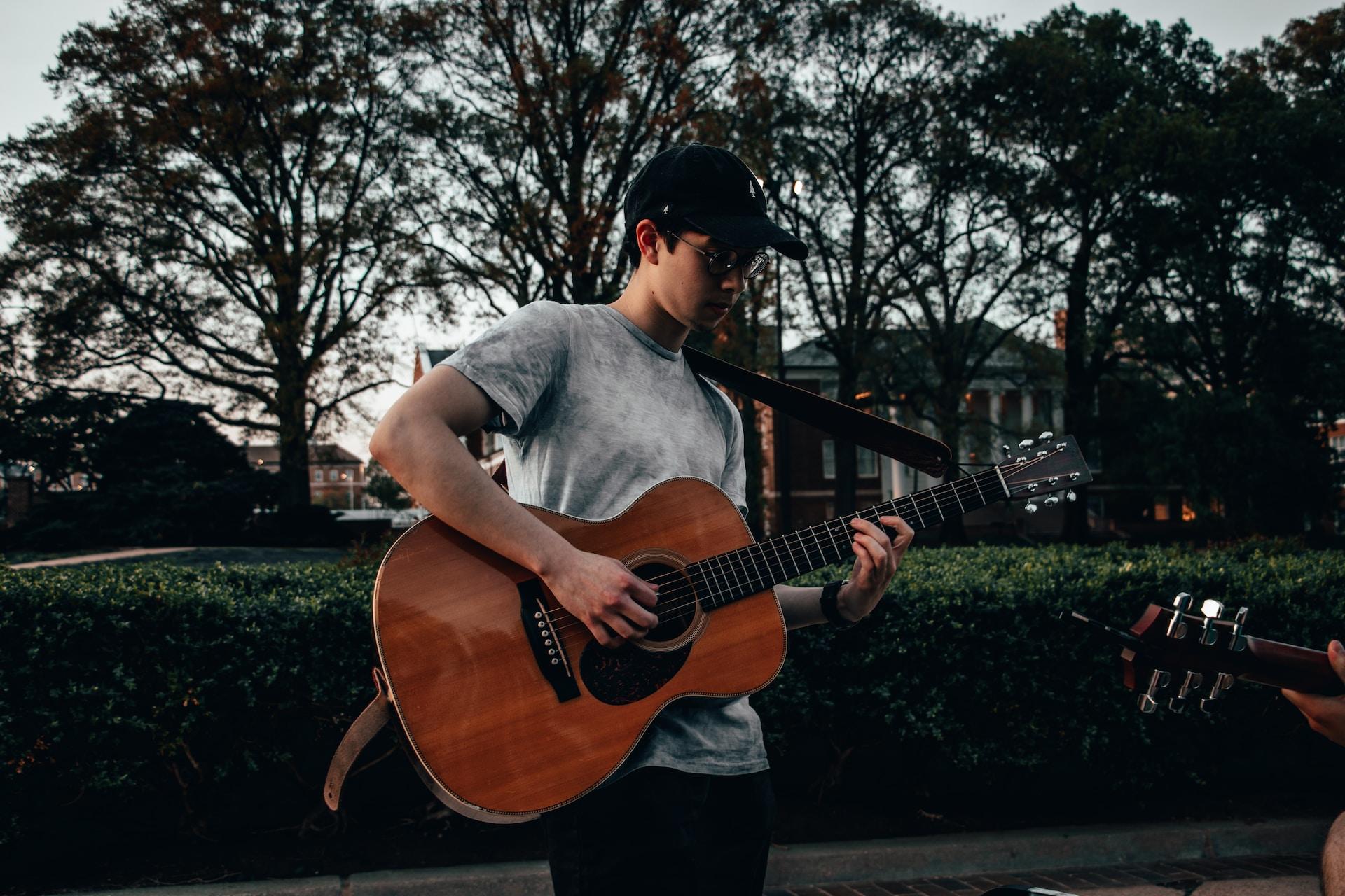 Jeune homme qui tient une guitare debout.
