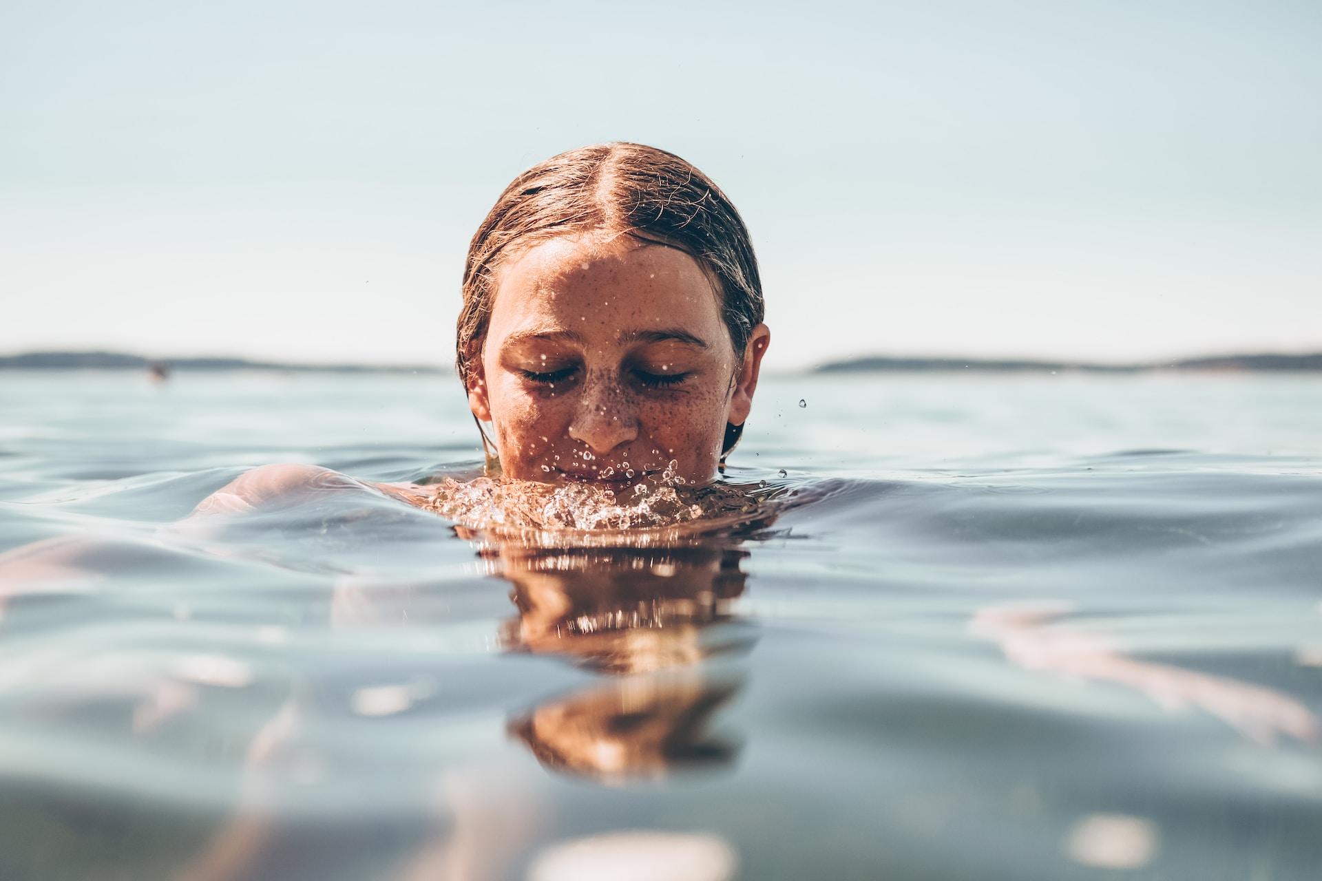 femme nageant dans l'eau et riant