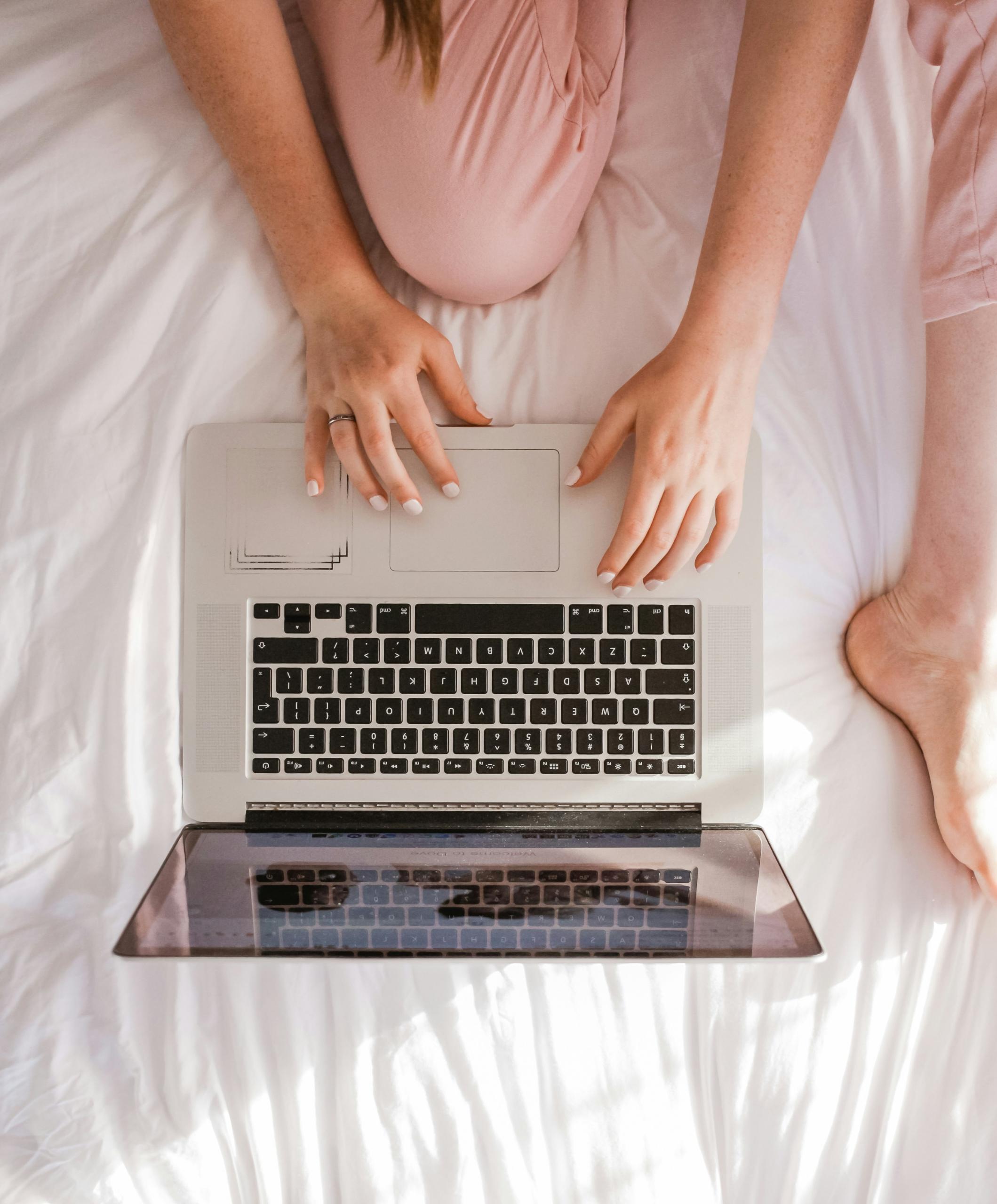 femme sur son lit travaillant avec laptop