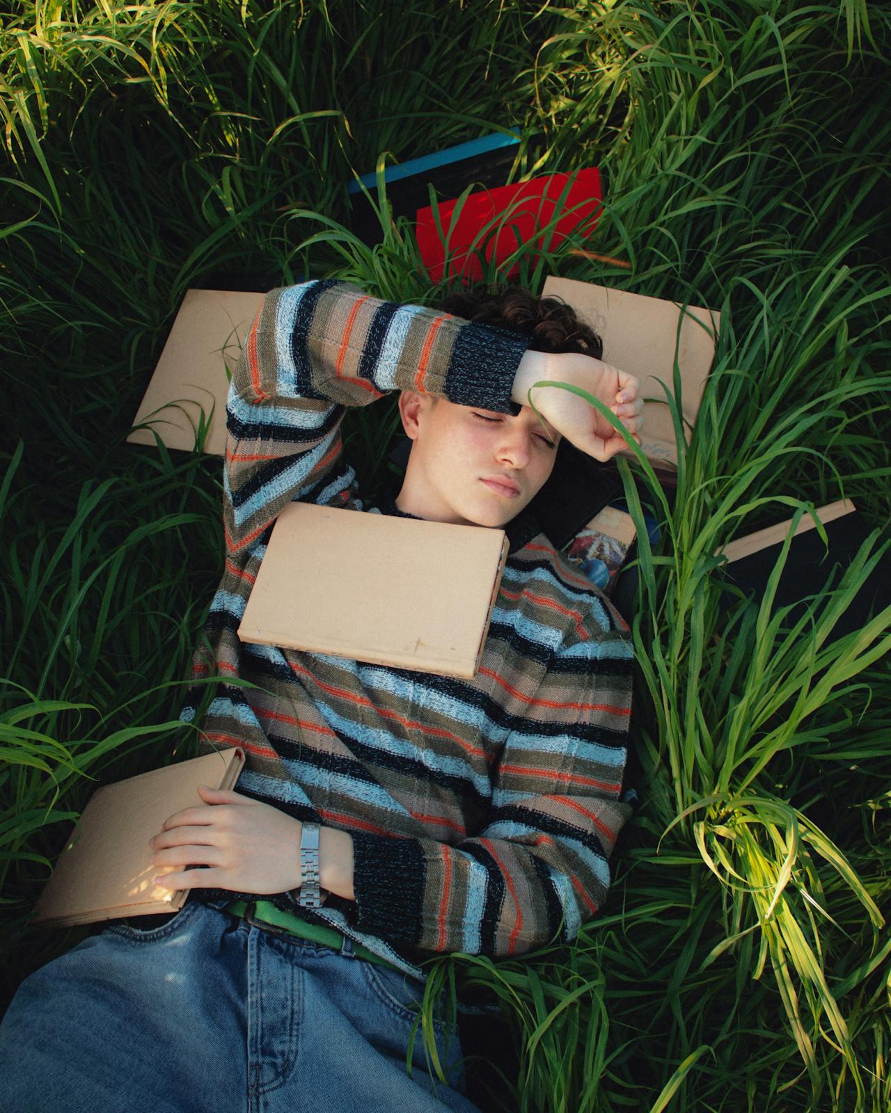 Une étudiante dans l'herbe avec des livres.