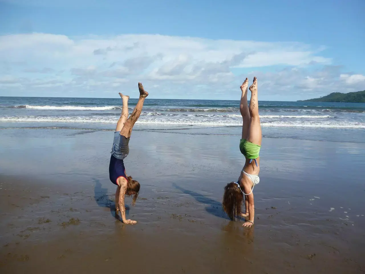 filles faisant du yoga tete en bas sur la plage