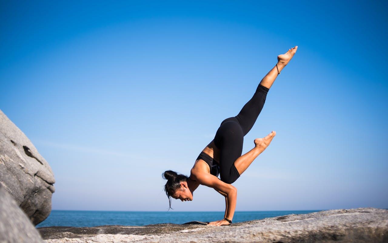 femme pratiquant pilates yoga sur les roches a la plage