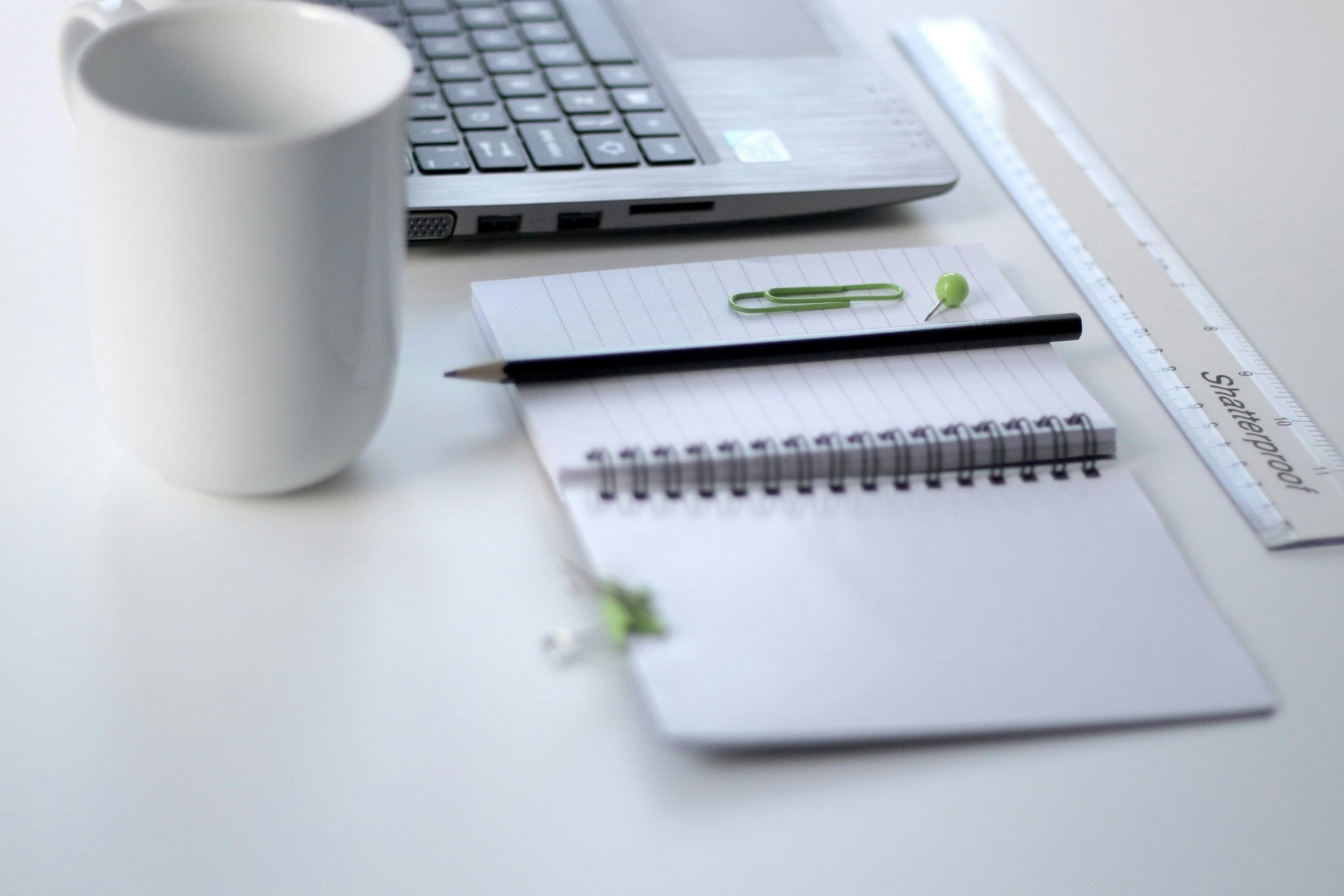 Un ordinateur et un cahier posés sur une table.