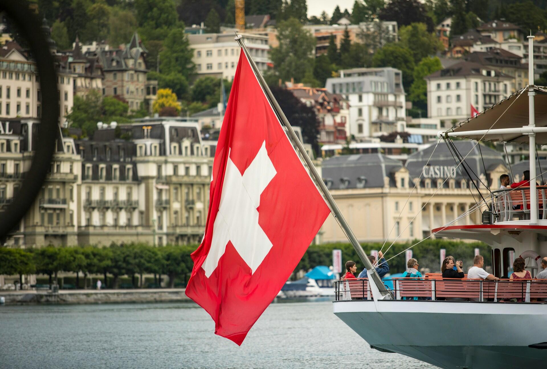 Drapeau suisse avec lac et ville en arrière plan.