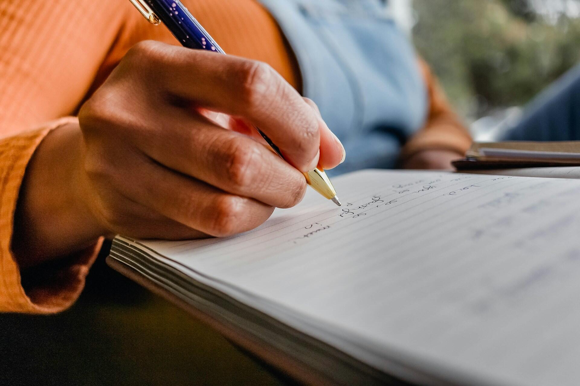 Focus sur une personne qui écrit dans son cahier de notes.