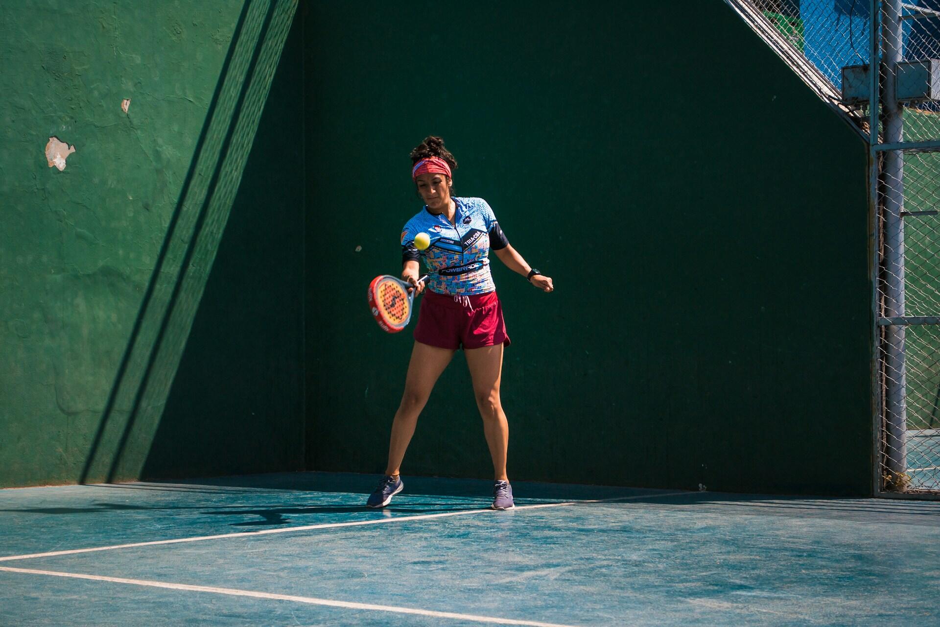 femme en tenue de sport dehors avec sa raquette sur le terrain de padel