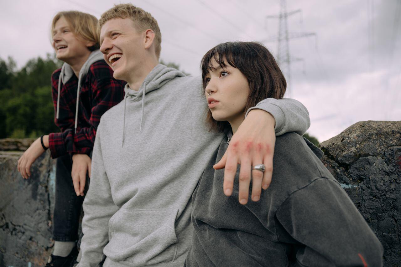 trois adolescents se tenant par les bras sous un ciel gris