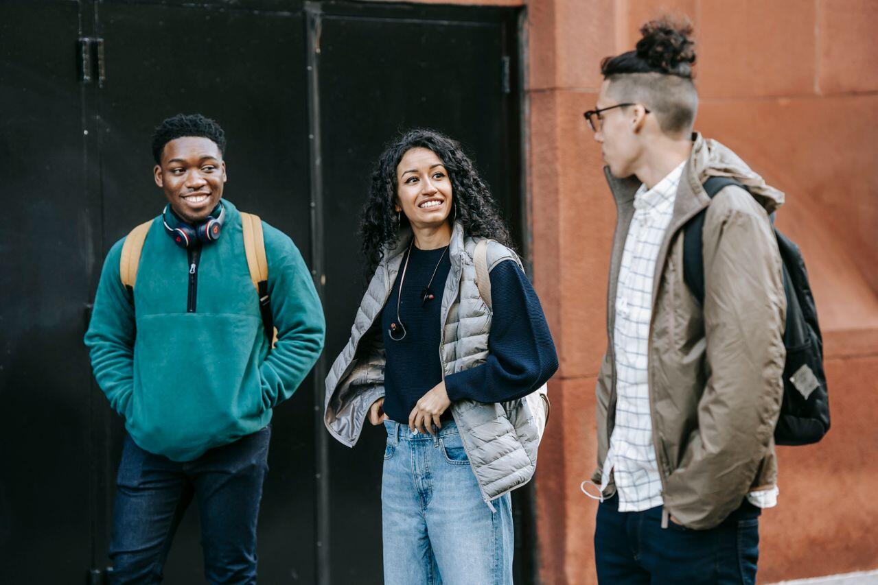 trois adolescents avec leurs sac en pleine conversation dehors