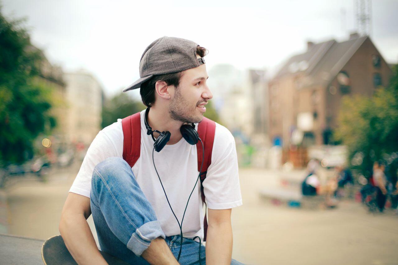 ado en tee shirt blanc casquette et sac a dos rouge