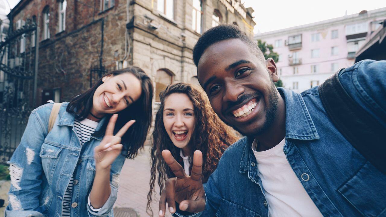 trois jeunes etudiants souriant faisant un selfie dehors