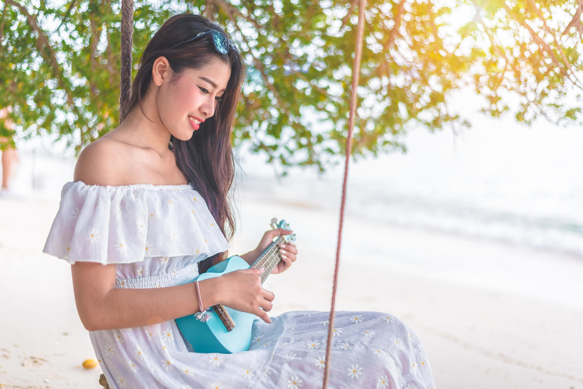 Mujer tocando el ukelele en la playa.
