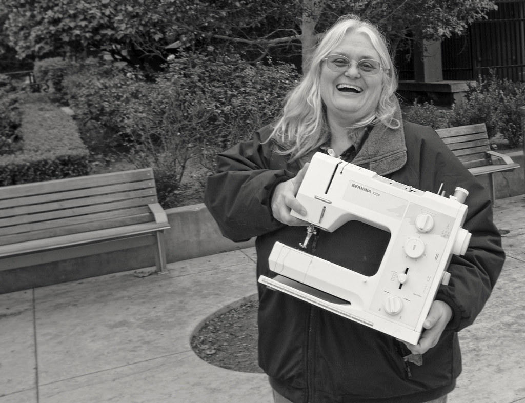 Mujer sonriente muestra máquina de coser